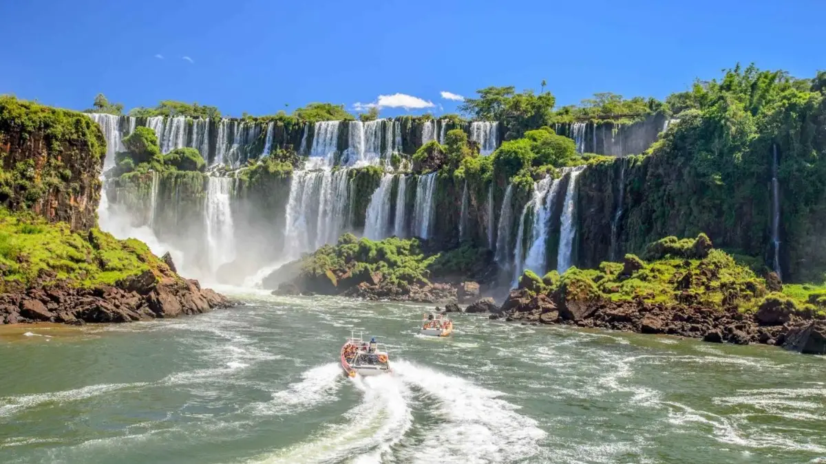 Adventure in the Iguazu Falls A panoramic view of the Iguazu Falls and tourists enjoying their boat ride