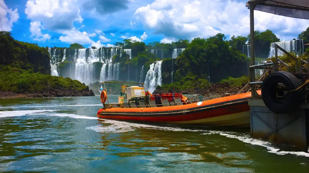 Boat ride on the Argentine side of the Breathtaking Iguazu Falls, surrounded by blue sky and lush forest