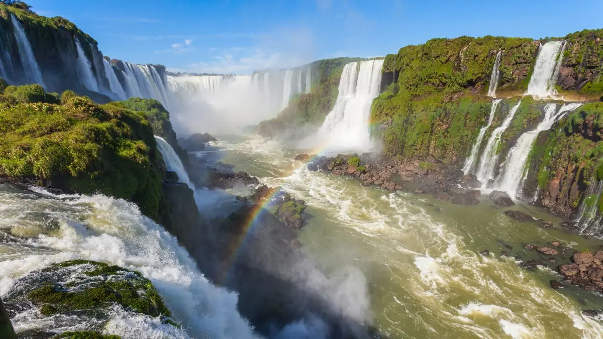 Iguazu Falls from Brazil A wide-angle view of the Iguazu Falls from the Brazilian side with a magical rainbow appearing in the sky